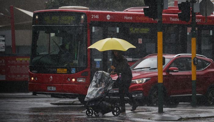A pedestrian pushing a baby pram crosses a flooding intersection as heavy rains affect Sydney, Australia, October 6, 2022. — Reuters