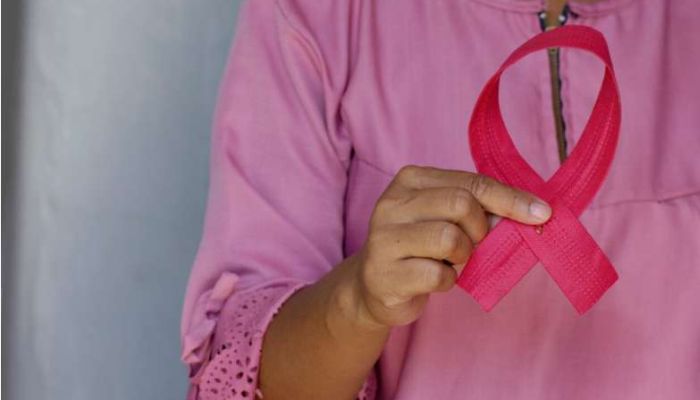 A woman holds a pink ribbon in her hand.— Unsplash