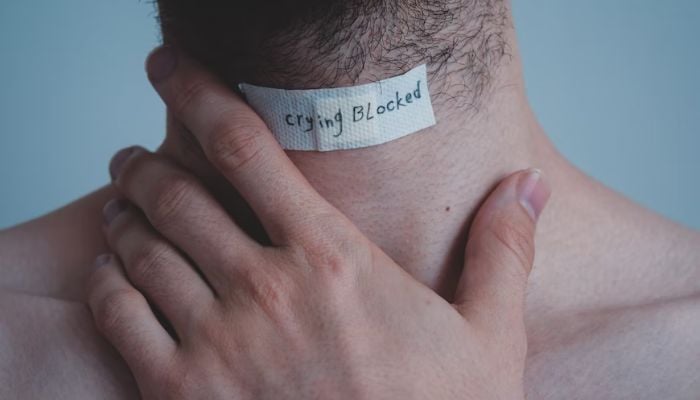 A man with his hand on his neck. — Unsplash