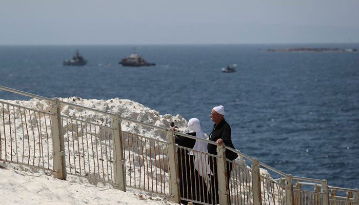 People walk as Israeli navy boats are seen in the Mediterranean Sea as seen from Rosh Hanikra, close to the Lebanese border, northern Israel May 4, 2021. — Reuters