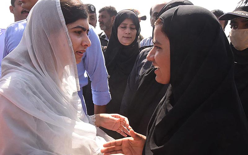 This handout picture taken and released by Chief Minister House Office of Sindh Province on October 12, 2022 shows Nobel Peace laureate Malala Yousafzai (L) meeting with a flood-affected girl at a makeshift camp in Johi, Dadu district of Sindh province. — AFP