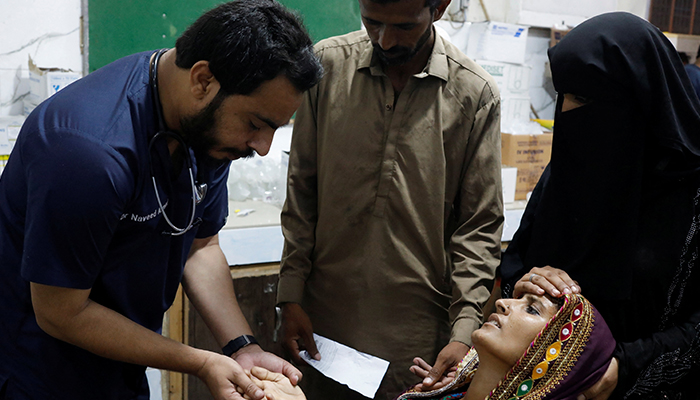 Naveed Ahmed, 30, a doctor, gives medical assistance to flood-affected woman Koonjh, 25, who is suffering from fever, at Sayed Abdullah Shah Institute of Medical Sciences in Sehwan, Pakistan September 29, 2022. — Reuters