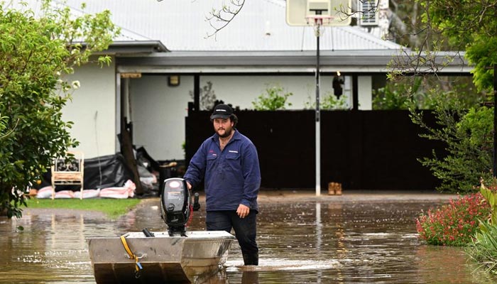 A man pushes a boat as floodwaters inundate a Victorian residential area amidst evacuation orders in Rochester, Australia, October 14, 2022. — Reuters