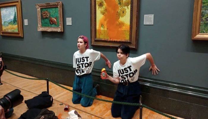 Activists of Just Stop Oil glue their hands to the wall after throwing soup at a van Goghs painting Sunflowers at the National Gallery in London, Britain October 14, 2022.— Reuters