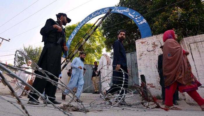 Police personnel stands in an alert position in front of a polling station during the NA-31 by-election in Peshawar, on October 16, 2022. — APP