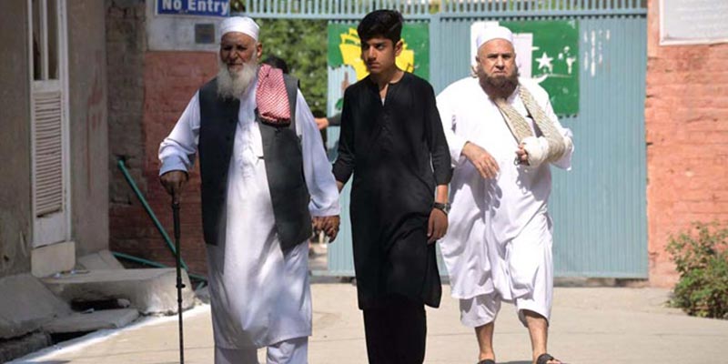 Relatives of a senior citizen going outside in a polling station in Peshawar after casting his vote during the NA-31 election, on October 16, 2022. — APP