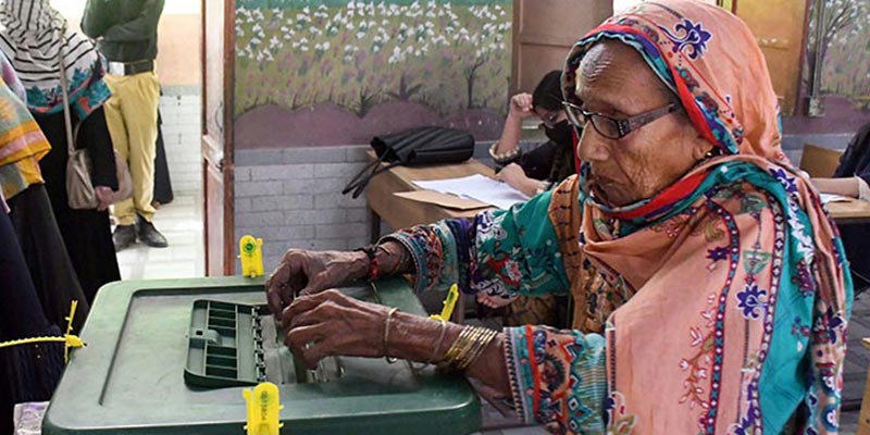 16 اکتوبر 2022 کو کراچی میں قومی اسمبلی کے حلقوں میں ضمنی انتخابات کے دوران ایک بزرگ خاتون پولنگ اسٹیشن پر بیلٹ باکس میں اپنا ووٹ ڈال رہی ہے۔ — آن لائن