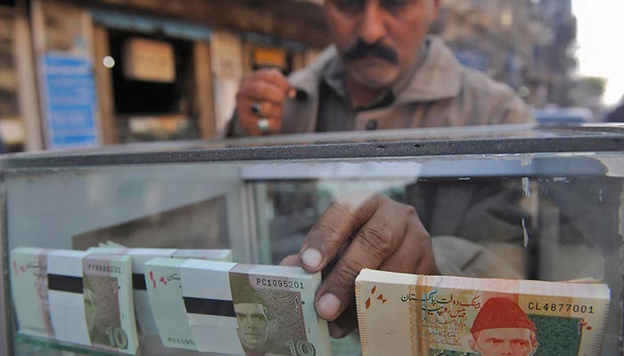 A vendor arranges 10 and 20-rupee Pakistani bank notes in a display shelf at a commercial area in Karachi, Pakistan, on December 14, 2011. — AFP/File