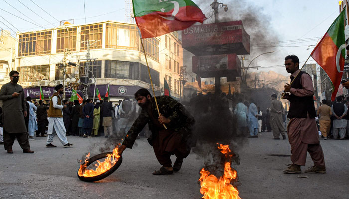 Activists of PTI party burn tyres during a protest against the disqualifying decision of former prime minister Imran Khan on a street in Quetta on October 21, 2022. — AFP