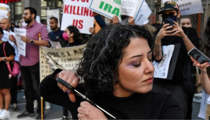 A woman cuts her hair during a protest against the Islamic regime of Iran and the death of Mahsa Amini in New York on Sept 27.— Reuters