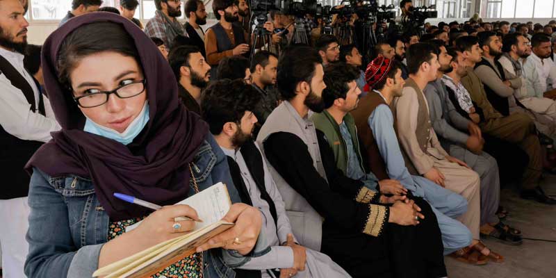 In a room full of men, an Afghan female journalist covers a presser by the Taliban officials in Kabul on 5 October 2021. Reuters/File