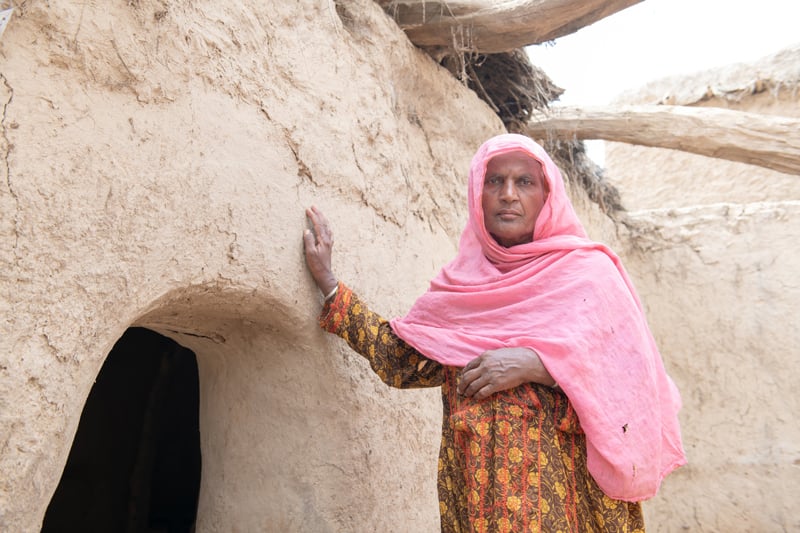 Malooka Khatoon, 70, a farmer, stands next to what is now left of her house in Village Pat Karira. — Helpage