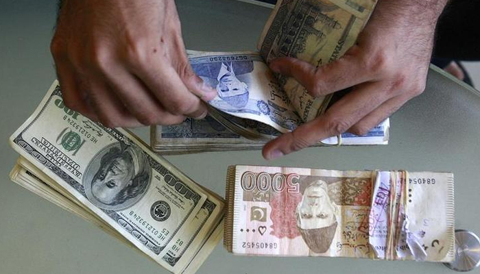 A currency dealer counts Pakistani rupees and U.S. dollars at his shop in Karachi, October 8, 2008. — Reuters