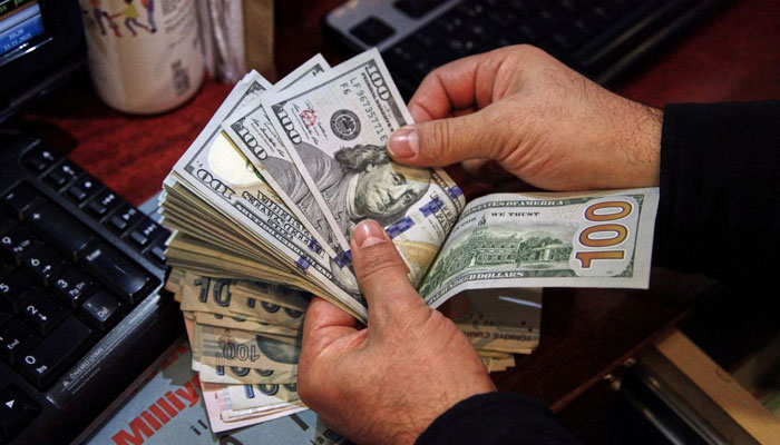 A representational image of a currency dealer counting $100. —Reuters/File