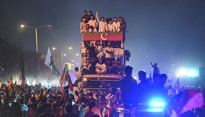 پی ٹی آئی کے چیئرمین عمران خان (سی ٹاپ) 26 مئی 2022 کو اسلام آباد میں ایک ریلی کی قیادت کرتے ہوئے بس کے اوپر سے حامیوں کو ہاتھ ہلا رہے ہیں۔ — اے ایف پی