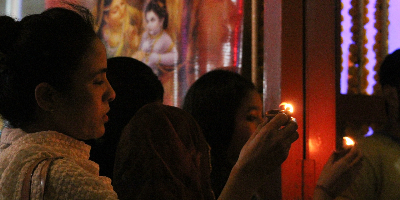 A female devotee lights up a diya during the Lakshmi Puja. — Photo by author