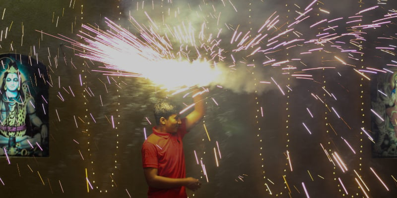 A young man swirls a cold firework lightening up the space. — Photo by author