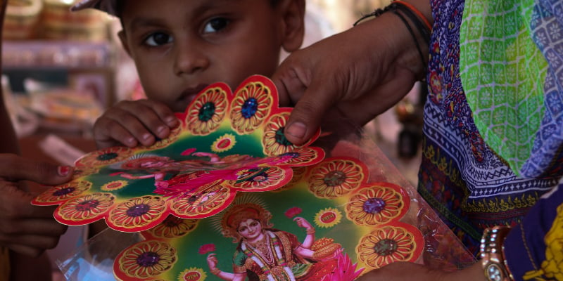 A child looks on as his mother buys decorative stickers with images of the Hindu deity Goddess Lakshmi. — Photo by author