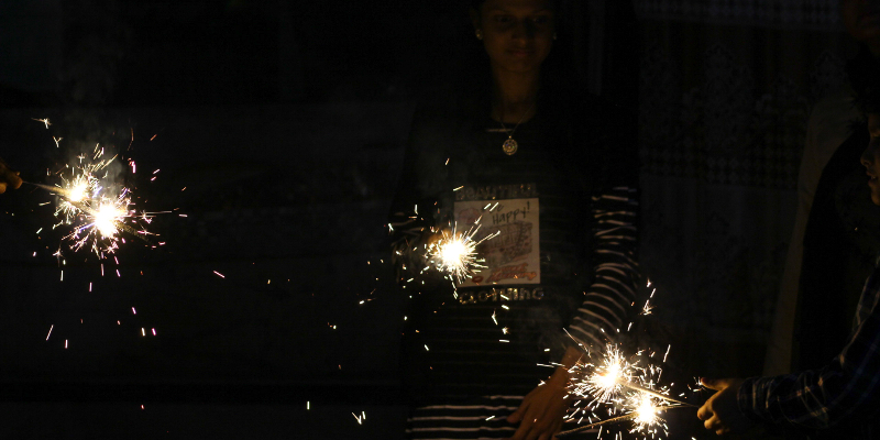 Women light up sparklers near the temple’s residential colony. — Photo by author