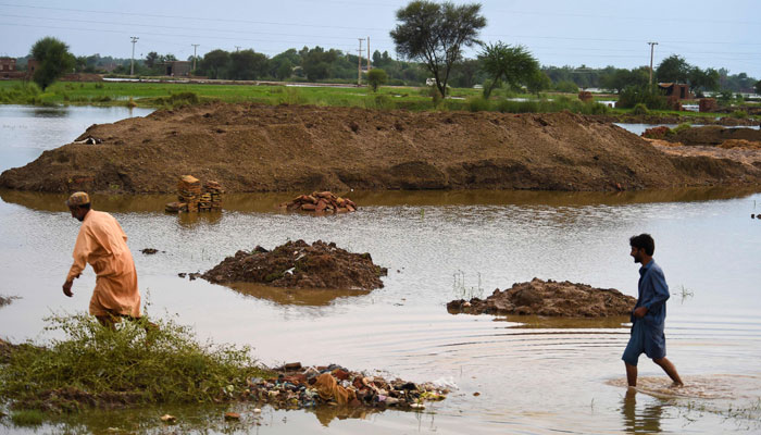 In this picture taken on August 26, 2022, labourers walk past a brick kiln factory damaged by flood waters due to heavy monsoon rains in Jacobabad, Sindh province of Pakistan. — AFP/File