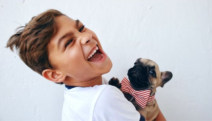 Boy happily holding his pet dog.— Unsplash