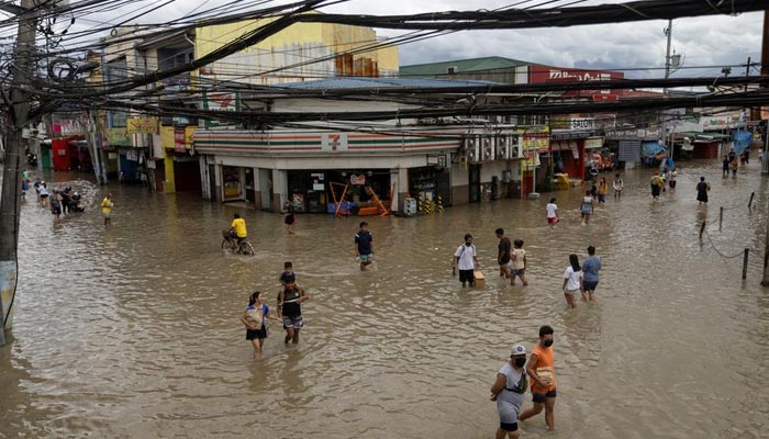 People wade through flooded streets following heavy rains tropical storm Nalgae, in Imus, Cavite province, Philippines, October 30, 2022. — Reuters
