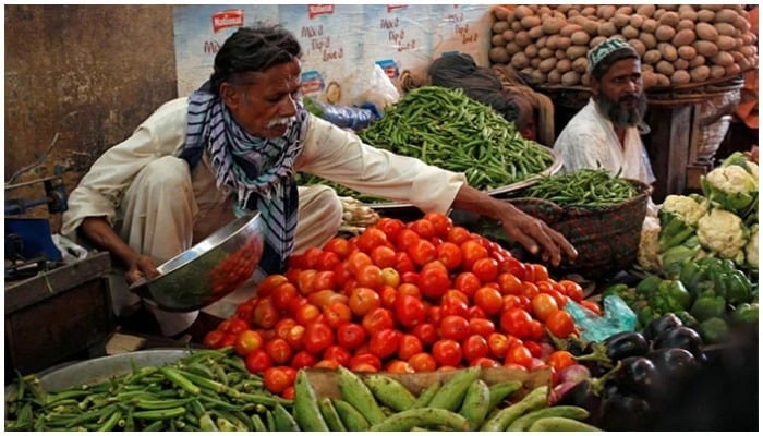 A vegetable vendor weighs vegetables at a stall. — Reuters/File