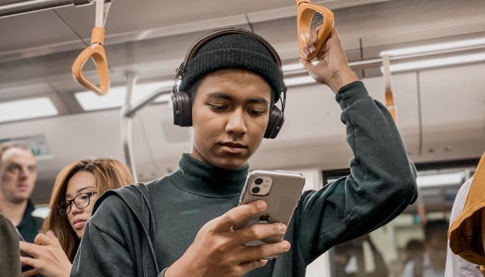 A young man using a smartphone on a public train somwehere in Singapore.— Unsplash