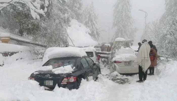 Locals stand next to vehicles sandwiched between snow and trees en route to Murree in this still image taken from a video, January 8, 2022. — PTV/Reuters TV via Reuters