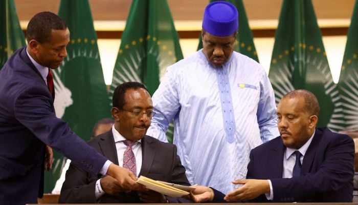 Ethiopian government representative Redwan Hussien and Tigray delegate Getachew Reda pass documents during the signing of the AU-led negotiations to resolve the conflict in northern Ethiopia, in Pretoria, South Africa, November 2, 2022.— Reuters