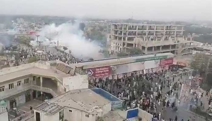 PTI workers and supporters clash with police and FC, while they shell teargas to disperse the angry crowd in Rawalpindis Faizabad Interchange. — Screengrab via YouTube/ Geo New Live