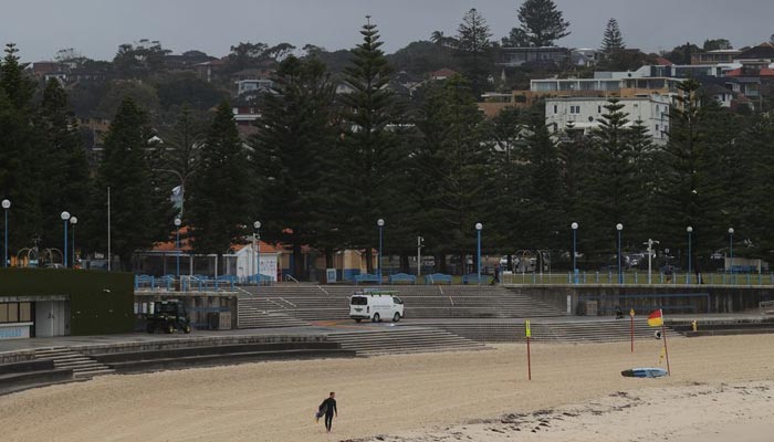 A person in a wetsuit walks along an empty Coogee Beach during stormy weather as heavy rains affect Sydney, Australia, October 6, 2022. — Reuters/File