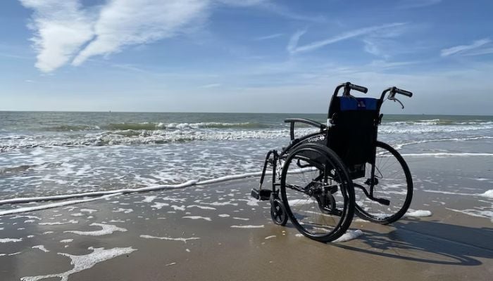 Black wheelchair on the beach.— Unsplash