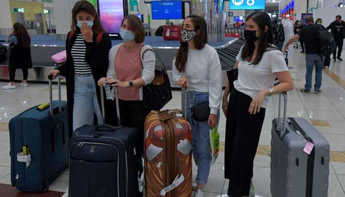 Passengers wait in queue to receive baggage in UAEs Dubai city. — AFP