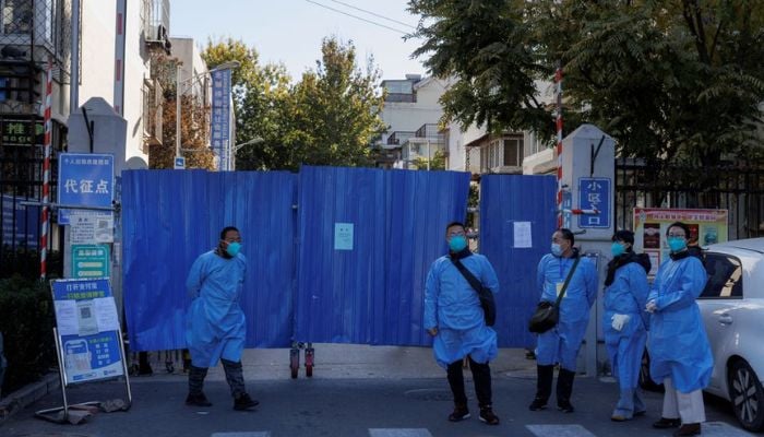 Officials wearing protective aprons stand outside the boarded-up gate of a residential compound that was placed under lockdown as outbreaks of coronavirus disease (COVID-19) continue in Beijing, November 7, 2022.— Reuters