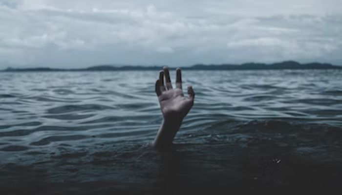 A persons hand emerges from under the ocean.— Unsplash