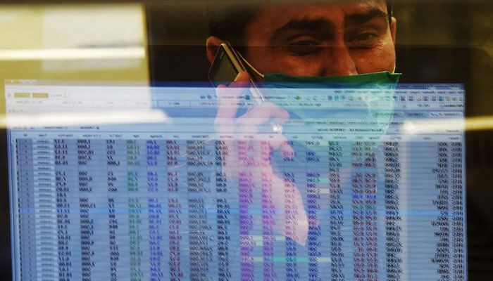 A stockbroker talks on the phone as he studies equities values on a trading screen at the PSX. — AFP/File