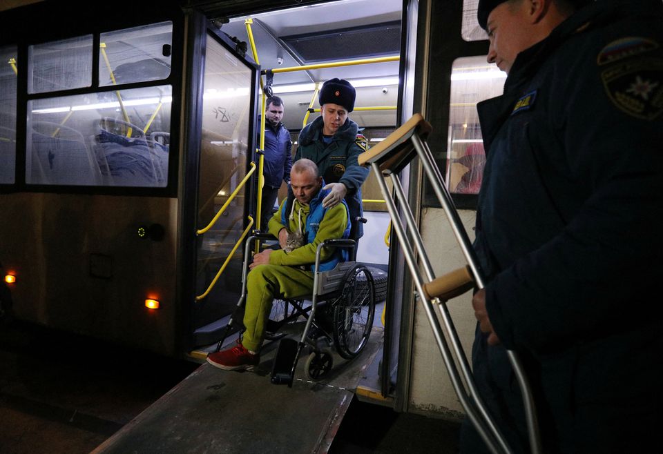 Members of the Russian Emergencies Ministry help a wheelchair user, who was evacuated from the Russian-controlled part of Kherson region of Ukraine, to leave a bus upon arrival at a local railway station in the town of Dzhankoi, Crimea November 10, 2022. — Reuters