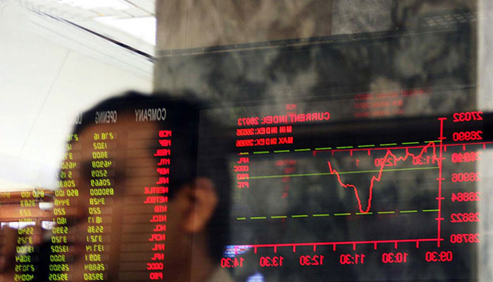 A stockbroker looks on as a trading screen is reflected on a glass pane at Pakistan Stock Exchange.— Reuters/File