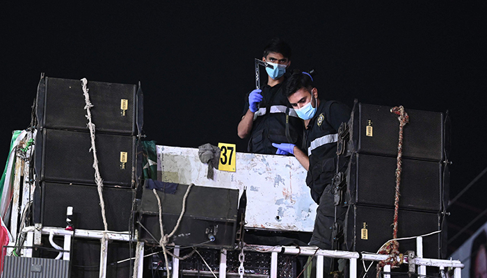 Investigators examine the roof top of a container truck used by the former Pakistani prime minister Imran Khan during his political rallies, hours after a gun attack in Wazirabad on November 3, 2022. — AFP