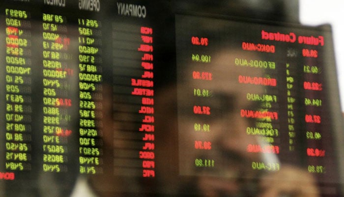 A stockbroker is mirrored in a trading screen at PSX as he talks on the phone. — Reuters/File