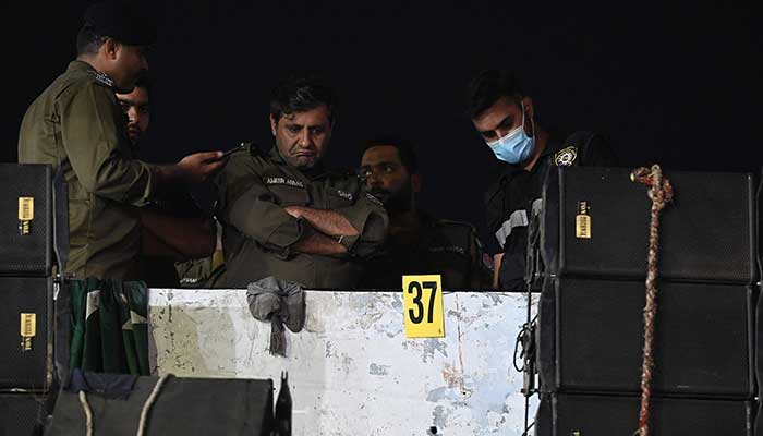 Investigators examine the rooftop of a container truck used by the former prime minister Imran Khan during his political rallies, hours after a gun attack in Wazirabad on November 3, 2022. — AFP