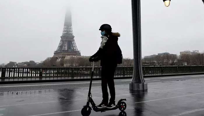 A woman rides an e-scooter with the Eiffel Tower in the backdrop in January 2021. — AFP