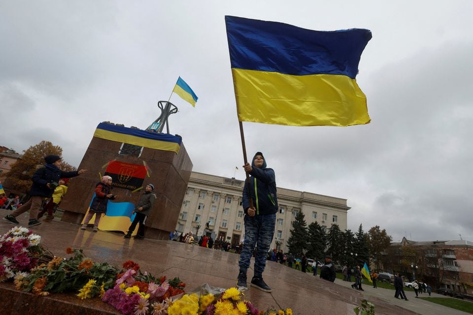 13 نومبر 2022 کو یوکرین کے وسطی کھیرسن میں روسیوں کے کھیرسن سے پسپائی کے بعد ایک لڑکا قومی پرچم لہرا رہا ہے۔— رائٹرز