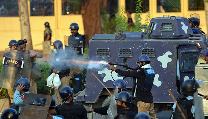A policeman (C) fires a tear gas shell toward supporters of Imran Khan and Canadian cleric Tahir ul Qadri during clashes near the prime ministers residence in Islamabad on August 31, 2014. — AFP/File