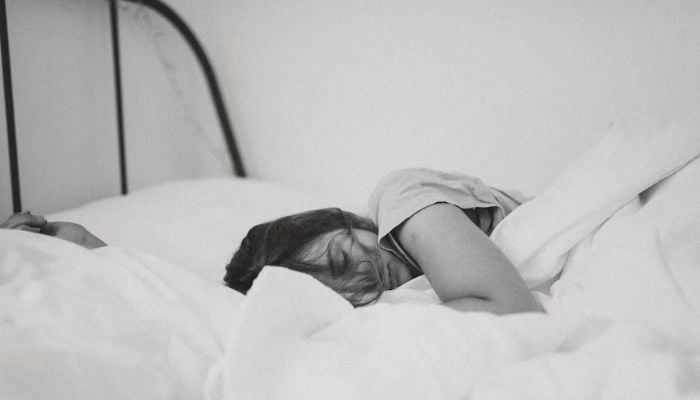 Seorang wanita tidur di tempat tidur.— Unsplash