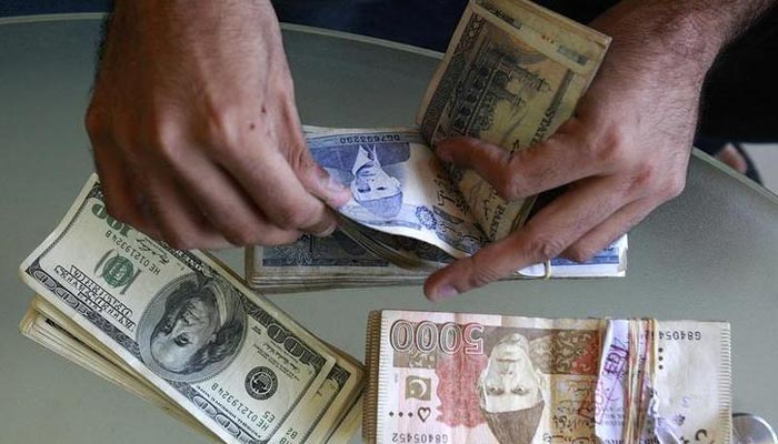 A currency dealer counts Pakistani rupees and U.S. dollars at his shop in Karachi October 8, 2008. — Reuters