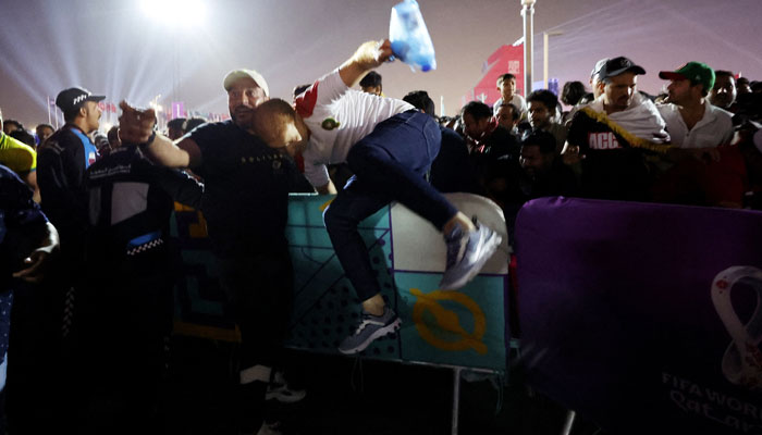 Fans jump over barriers away from a crowd gathered at the fan festival. — Reuters