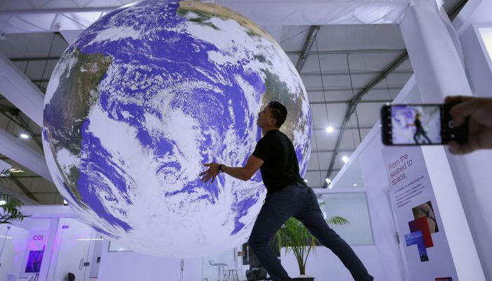 An attendee poses for a picture near model earth during the COP27 climate summit in Sharm el-Sheikh, Egypt November 19, 2022. — Reuters