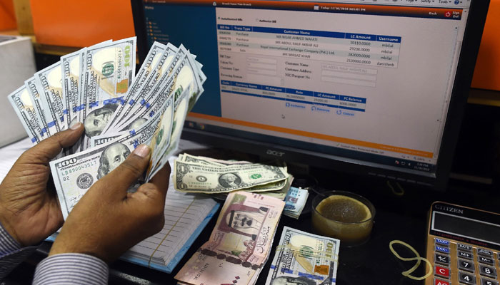 A Pakistani dealer counts US dollars at a currency exchange shop in Karachi. — AFP/File